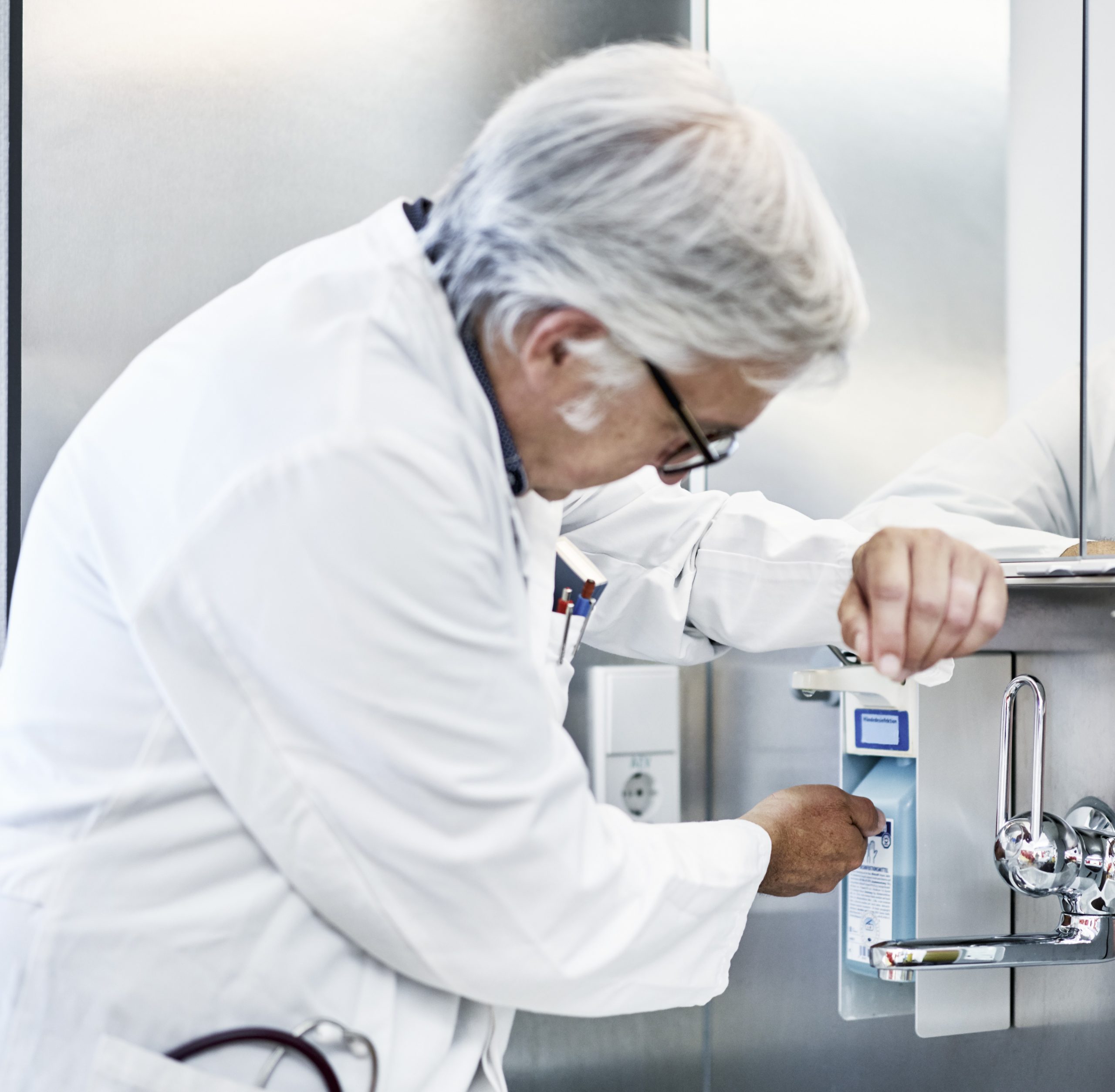 Krankenhaus mit Waschbecken Wasserhahn und Spender und Arzt bei der